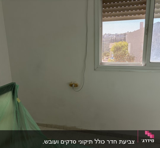 קיר צבוע עם חלון ויריעה ירוקה להגנה על הרצפה